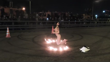 Naked girl shows fire show and striptease on the asphalt