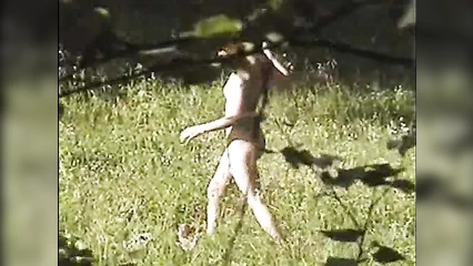 Nudist collects flowers in a clearing