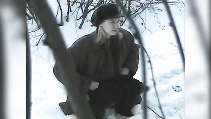 A girl in a retro hat pees in the forest in winter