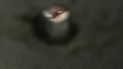 Concerned guy spies on chick through a hole in the wall