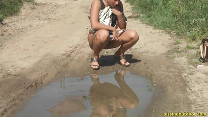 The blonde sat down to take a piss by the puddle